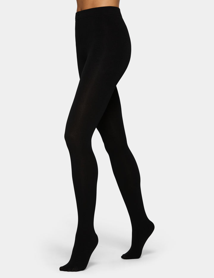 A model wearing black tights photographed against a light gray background.