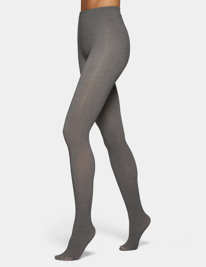 A model wearing dark grey tights photographed against a light gray background.