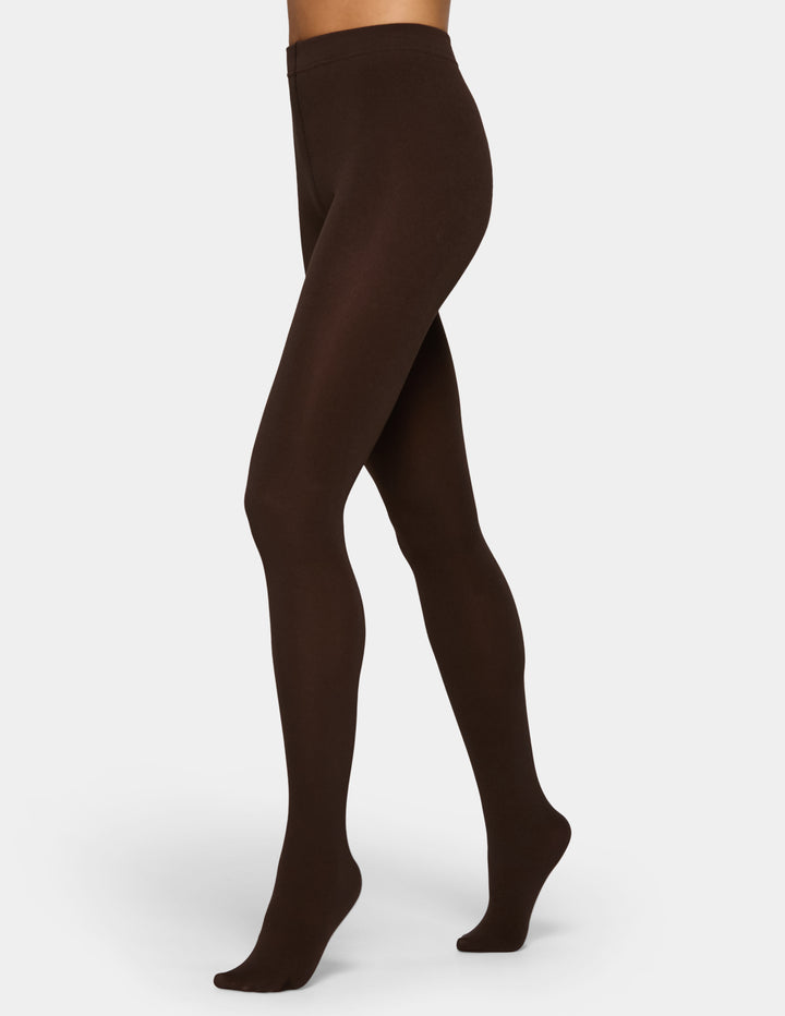 A model wearing brown tights photographed against a light gray background.