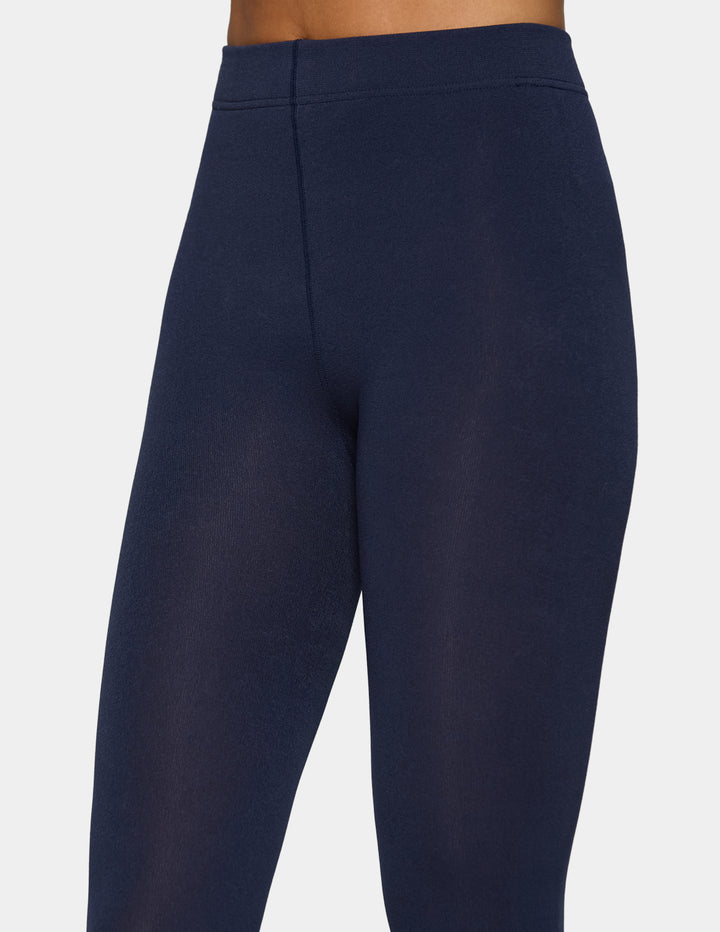 A close-up of a model wearing navy tights photographed against a light gray background.