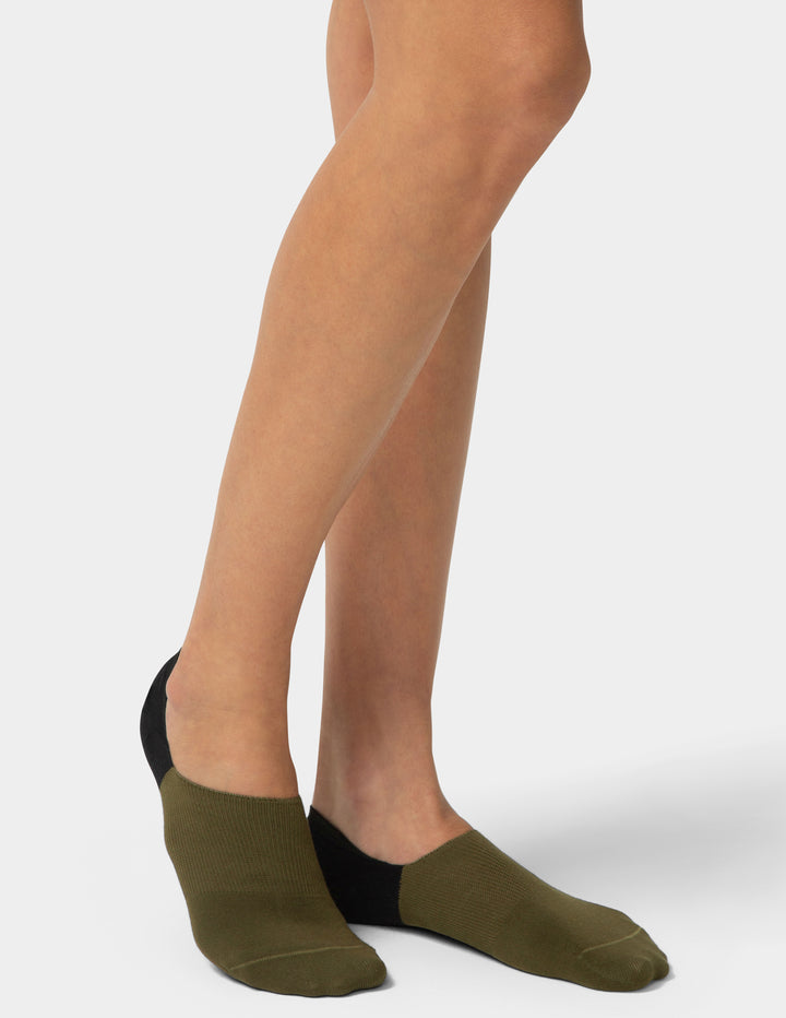 Person wearing olive green socks with a plain background