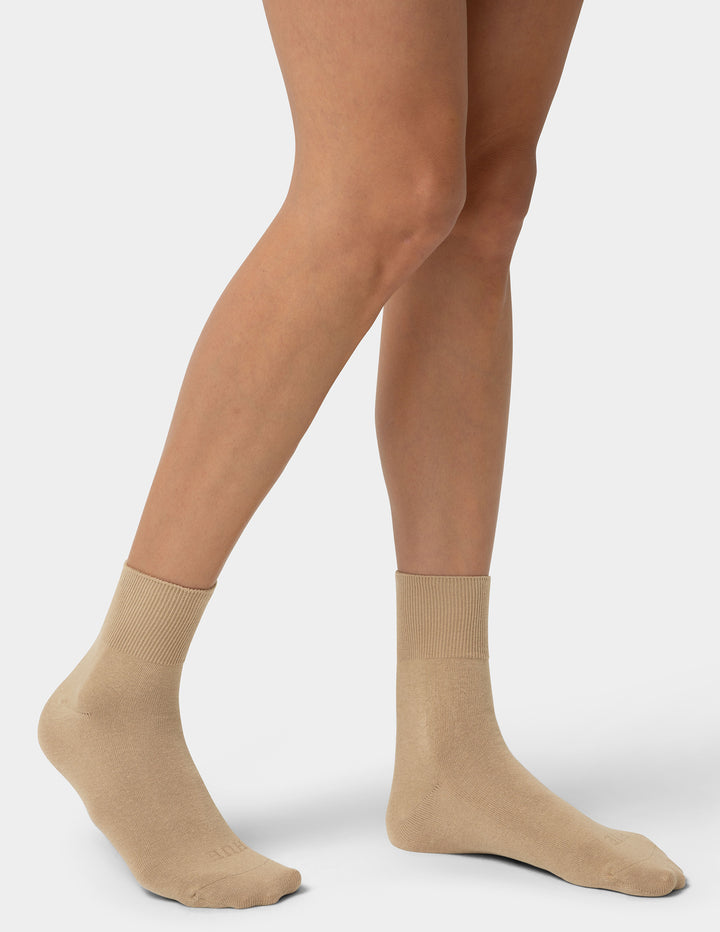 Beige socks worn by a person on a white background