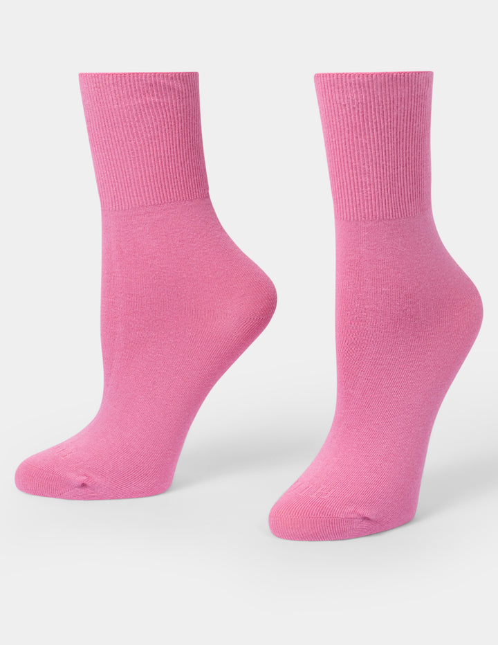 A pair of bright pink crew socks displayed on foot forms against a clean, light gray background.