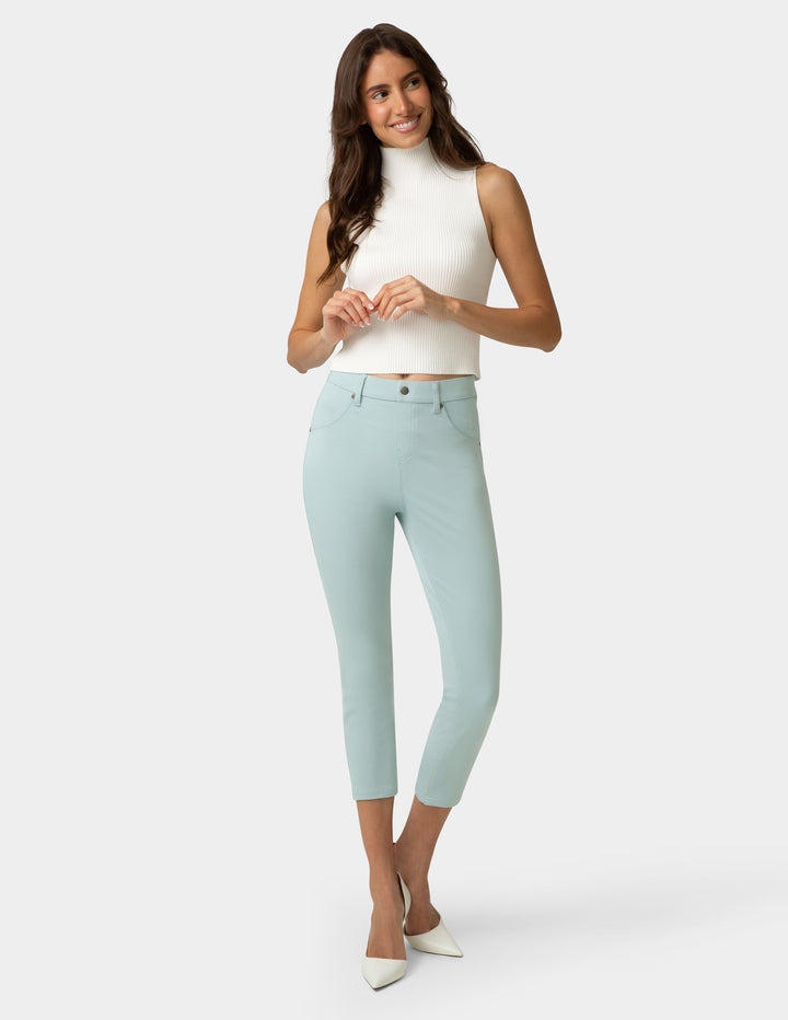 Woman wearing light blue jeans and a white top on a white background