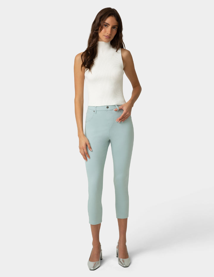 Woman wearing light blue capri pants and a white top on a white background