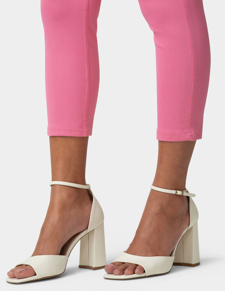 Beige high-heeled sandals worn with pink pants on a white background