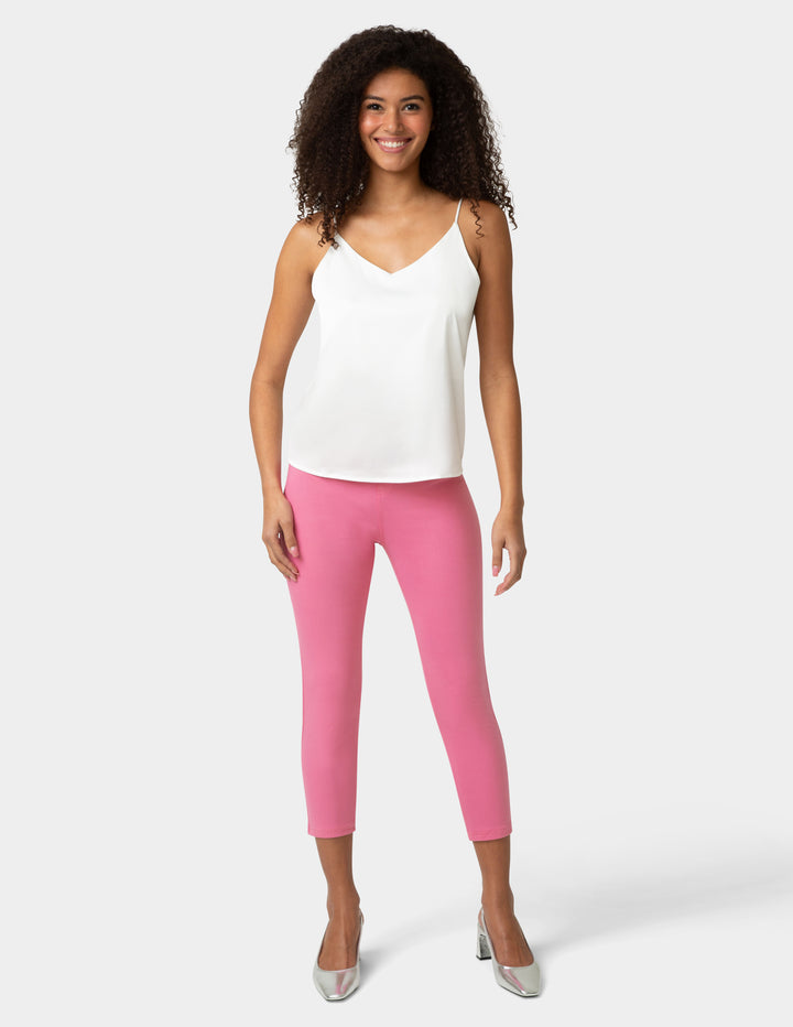 Woman wearing a white top and pink leggings on a white background