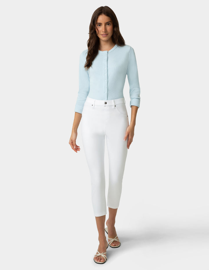 Woman wearing a light blue top and white pants on a white background