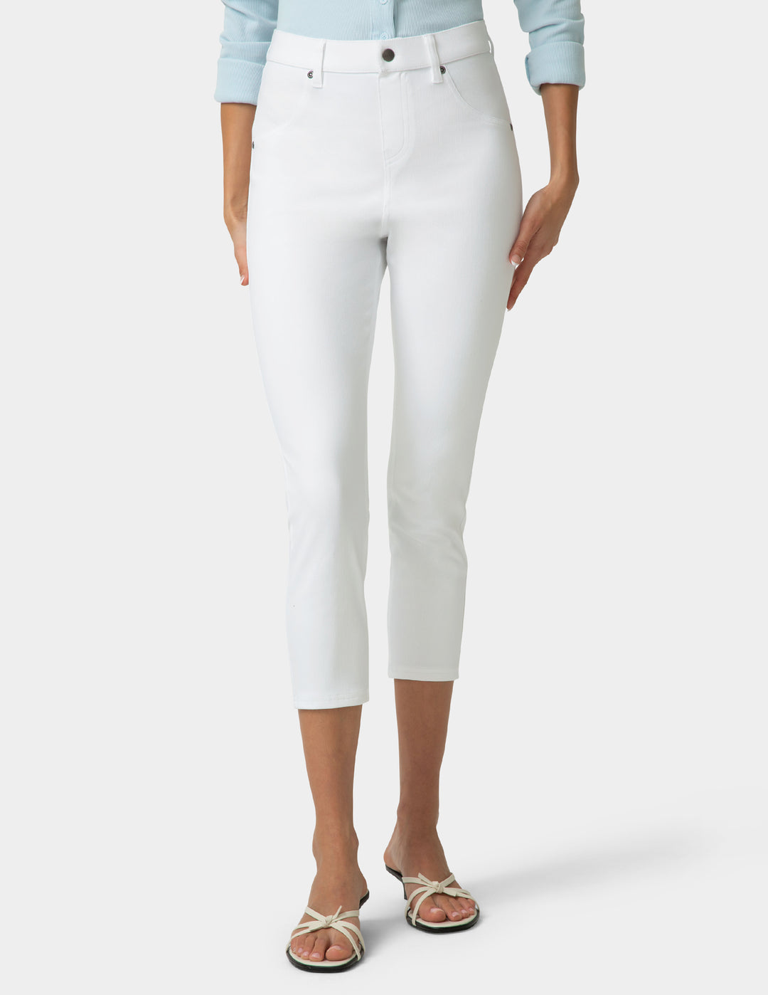 Person wearing white capri pants on a plain background