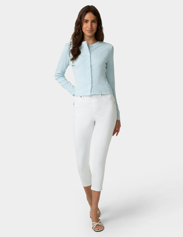 Woman wearing a light blue jacket and white pants on a white background