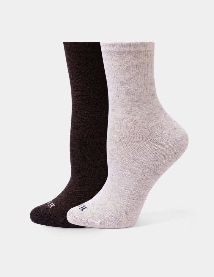 Two pairs of crew socks shown on invisible forms against a light gray background. The front pair is an off-white color, and the back pair is solid brown.