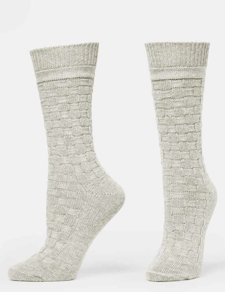 A pair of light beige textured crew socks with a basketweave knit pattern, shown from the side against a plain white background.