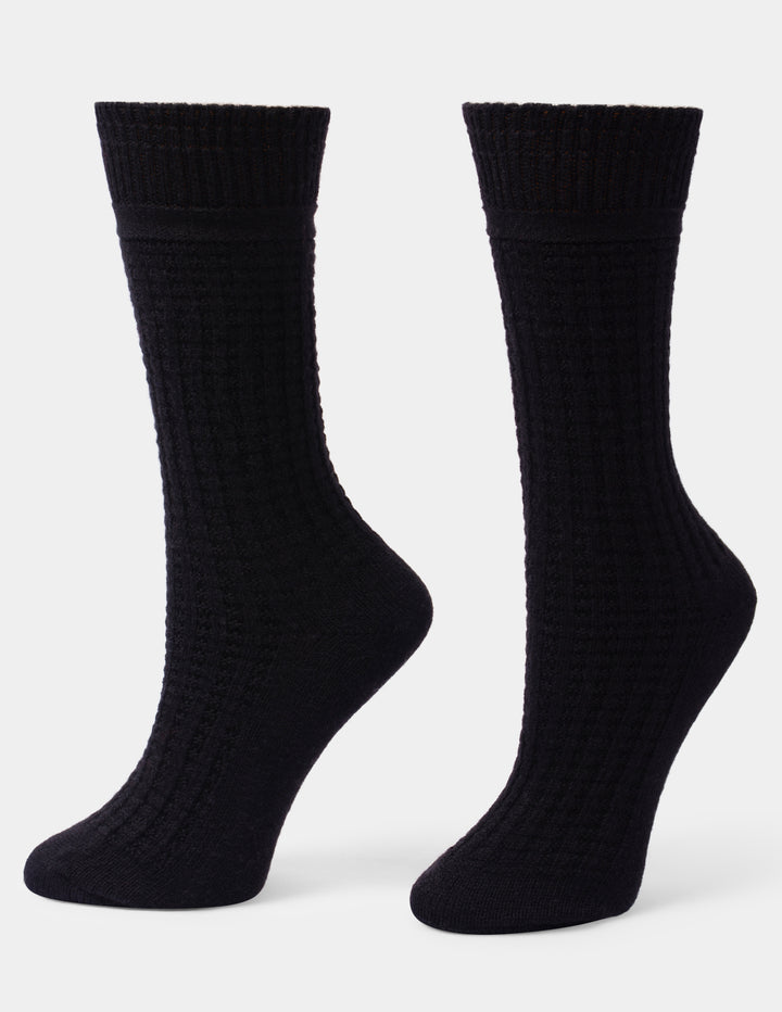 A pair of black ribbed crew socks displayed on invisible forms against a light gray background.