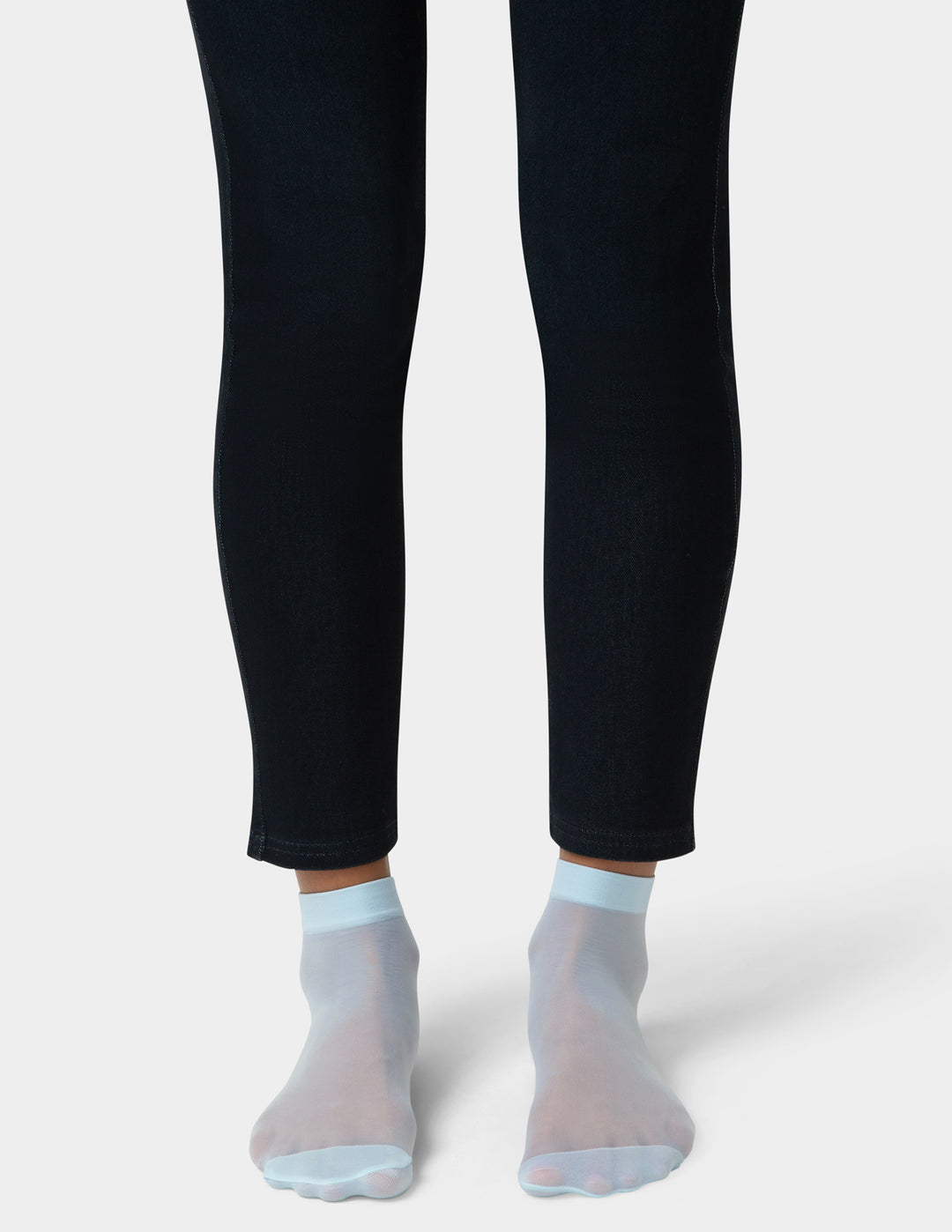 Person wearing black leggings and sheer blue socks on a white background