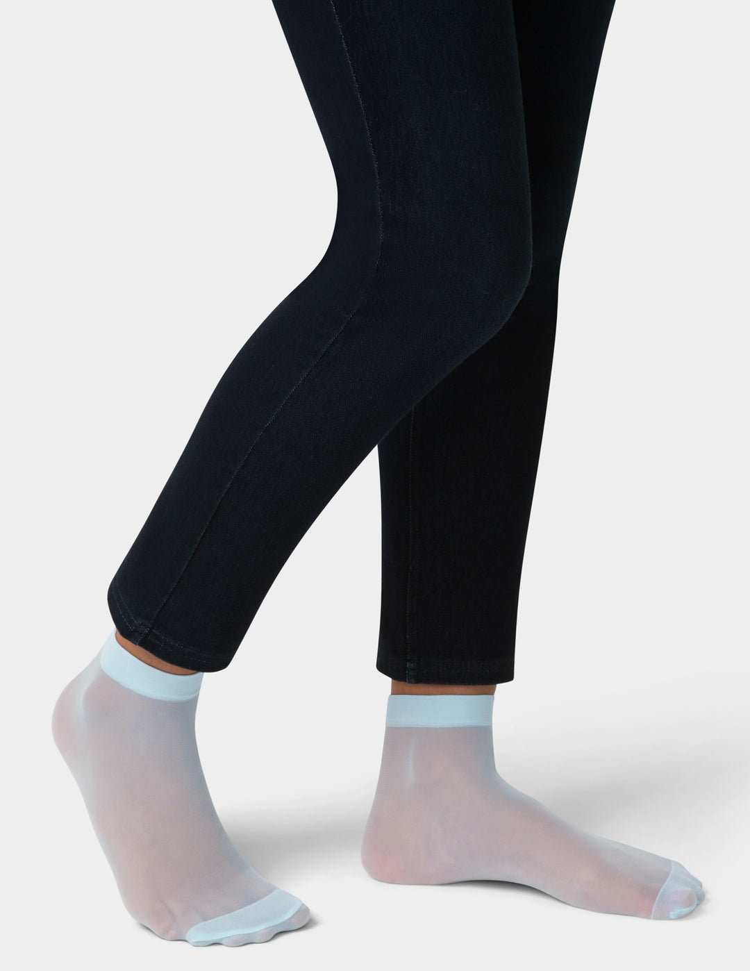Black leggings worn with sheer light blue socks on a white background