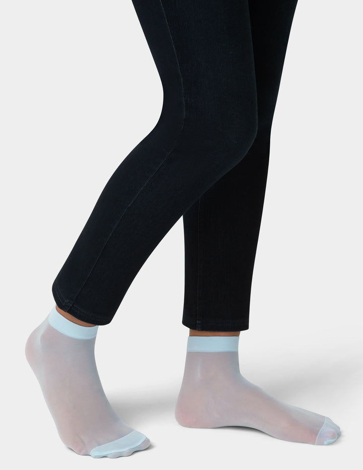 Black leggings worn with sheer light blue socks on a white background