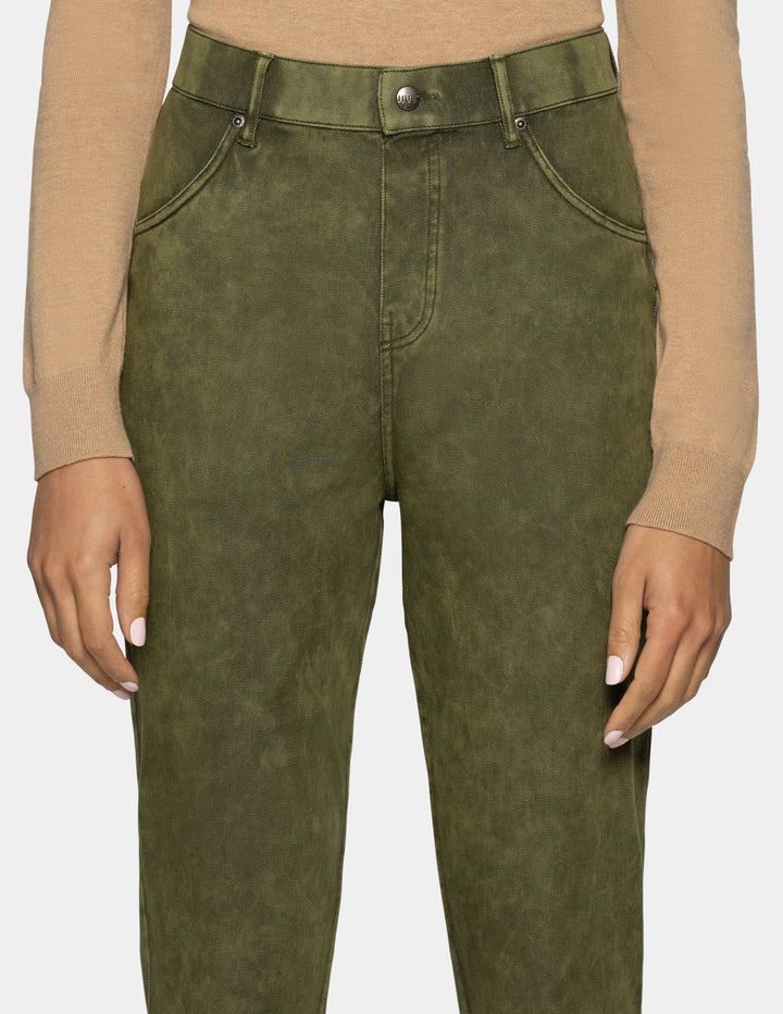 A close-up of a person wearing olive green high-waisted jeans with a washed finish, paired with a beige long-sleeve top against a light gray background.