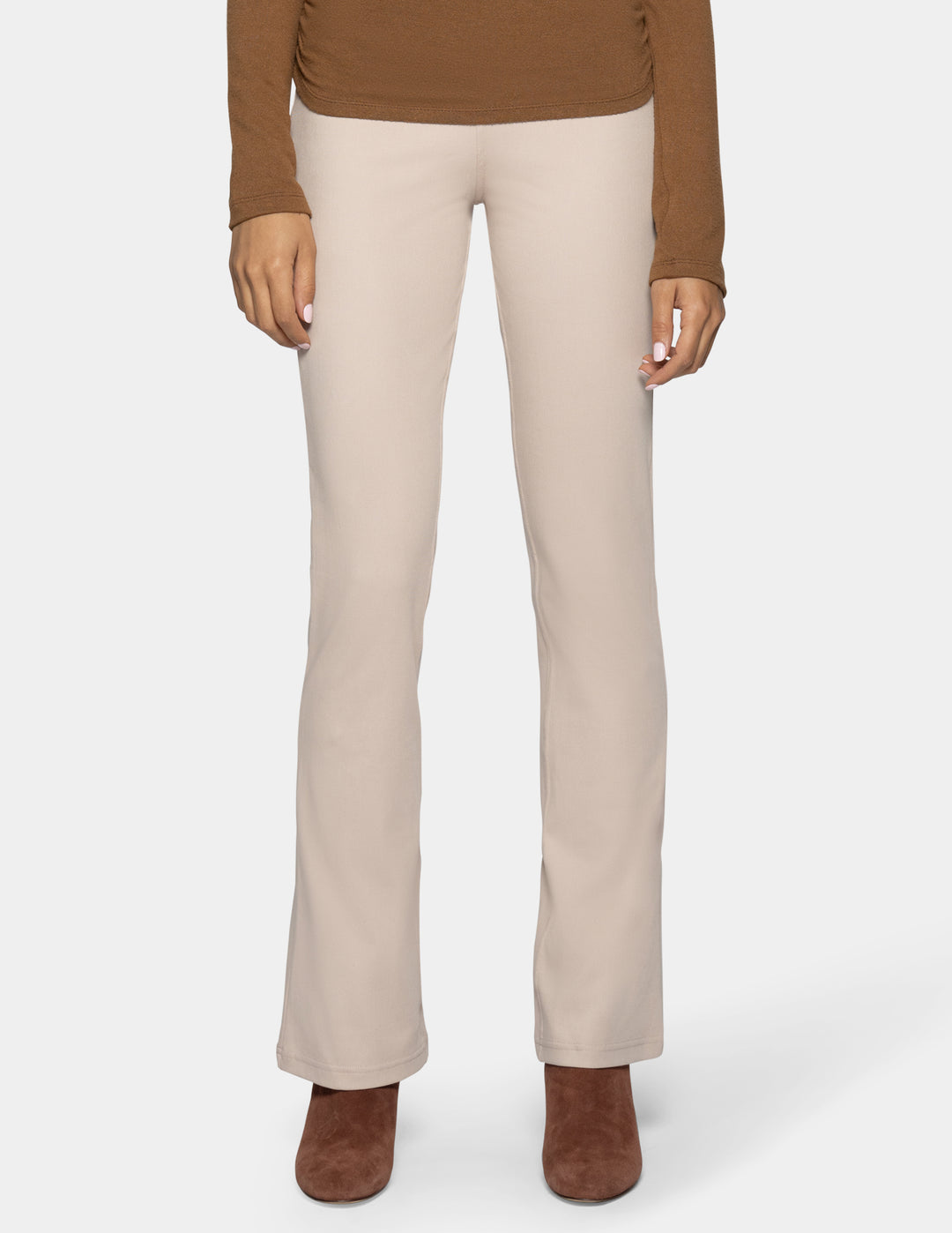 A model is shown from the waist down wearing light beige straight-leg pants, a brown long-sleeve top, and brown suede ankle boots against a light gray background.
