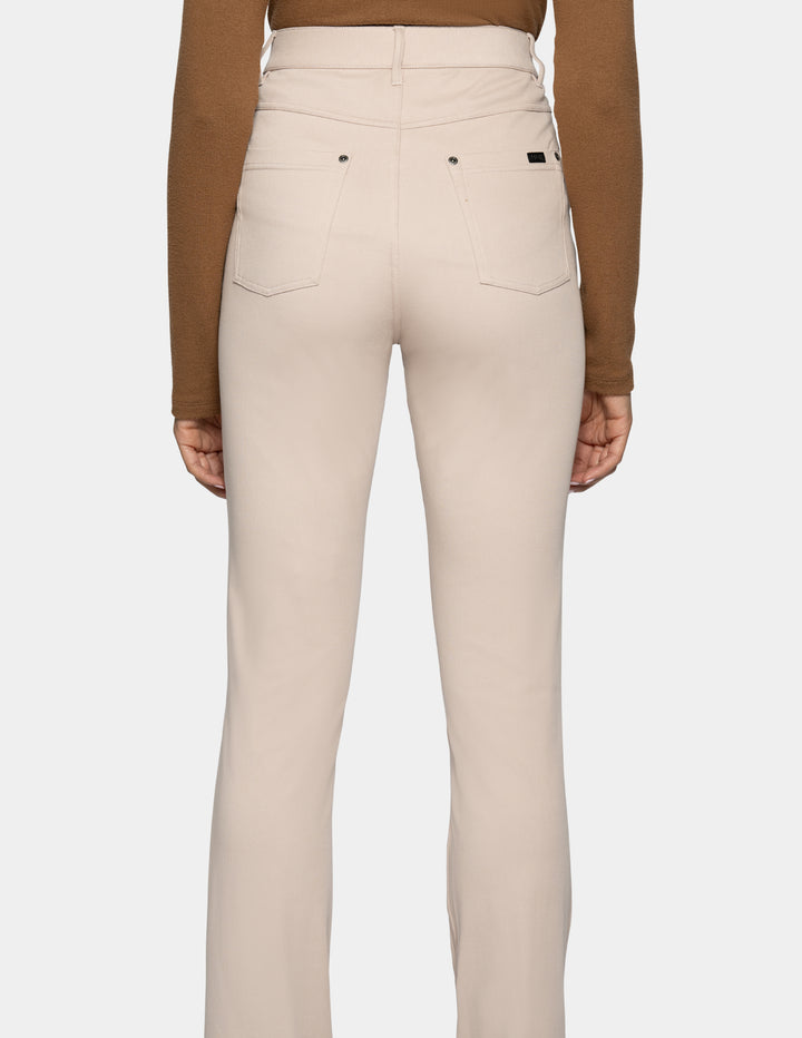 Rear view of a model wearing high-waisted beige pants with a brown long-sleeve top, shown against a light gray background.