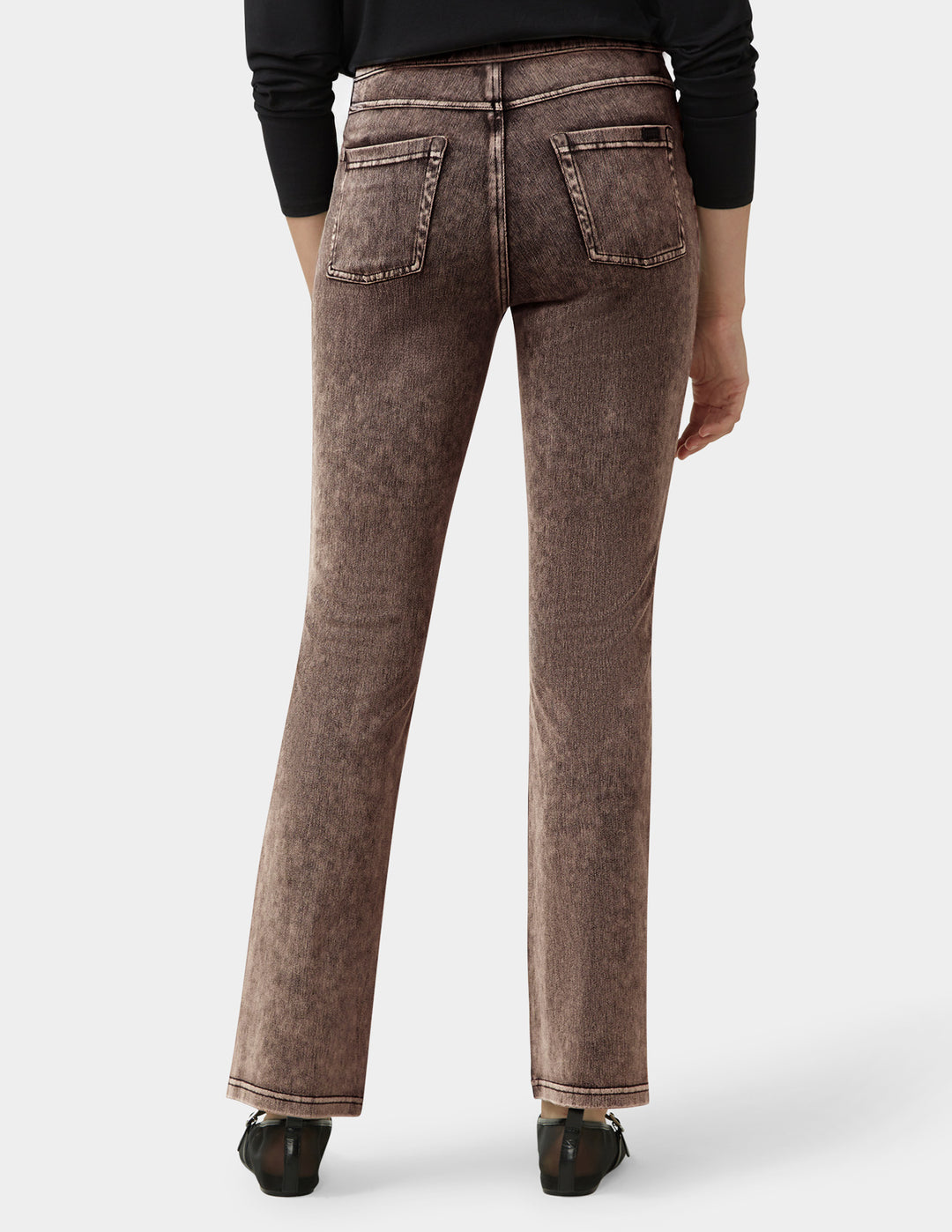 Brown jeans worn by a person on a white background