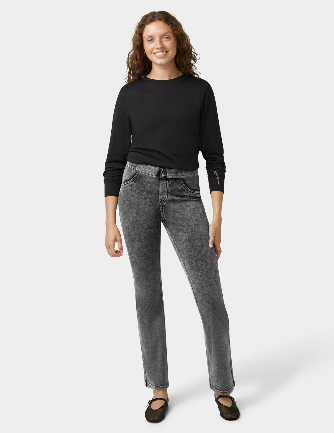 Woman wearing a black top and gray jeans on a white background