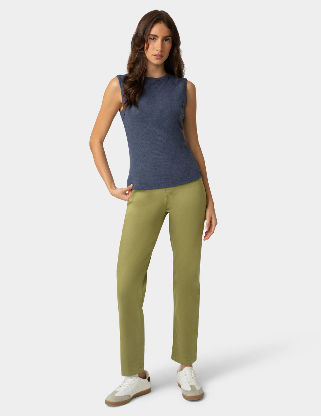 Woman wearing a blue sleeveless top and green pants on a white background