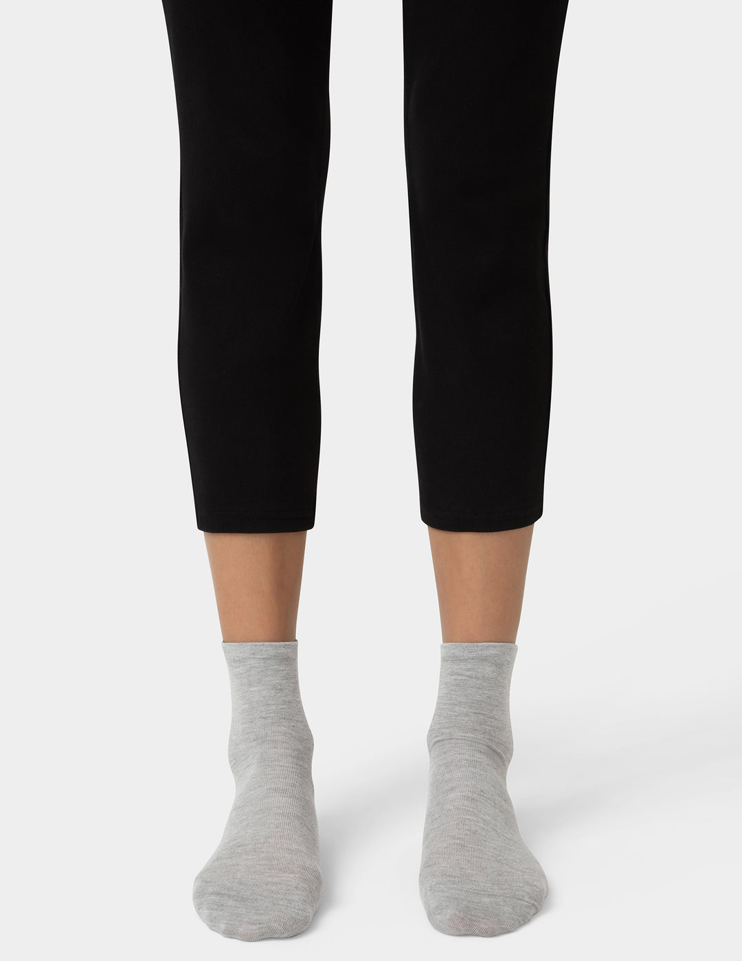 Person wearing black leggings and gray socks on a white background