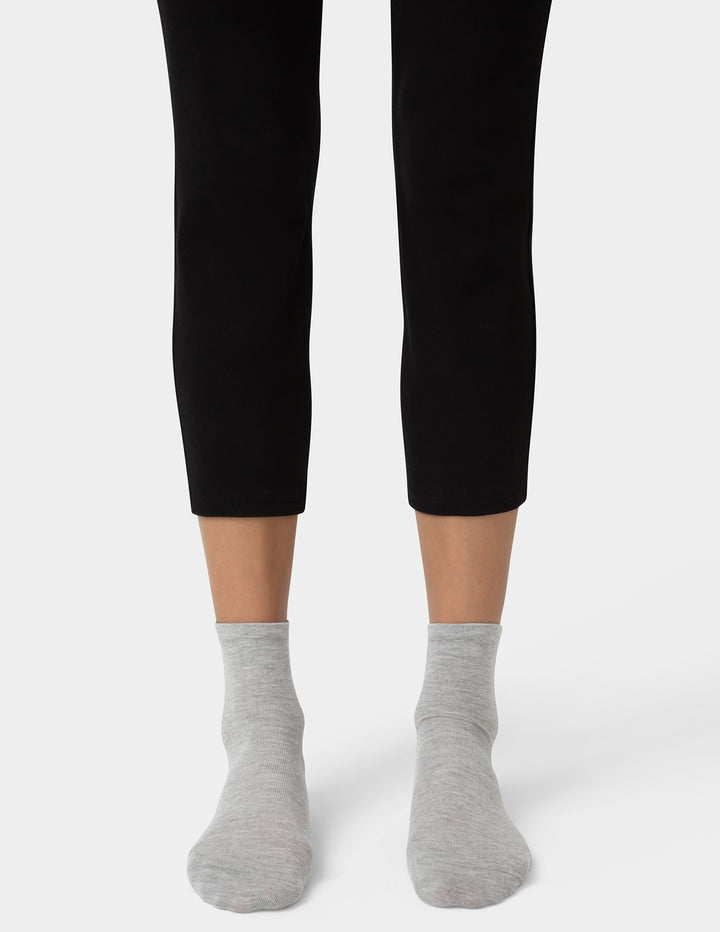 Person wearing black leggings and gray socks on a white background