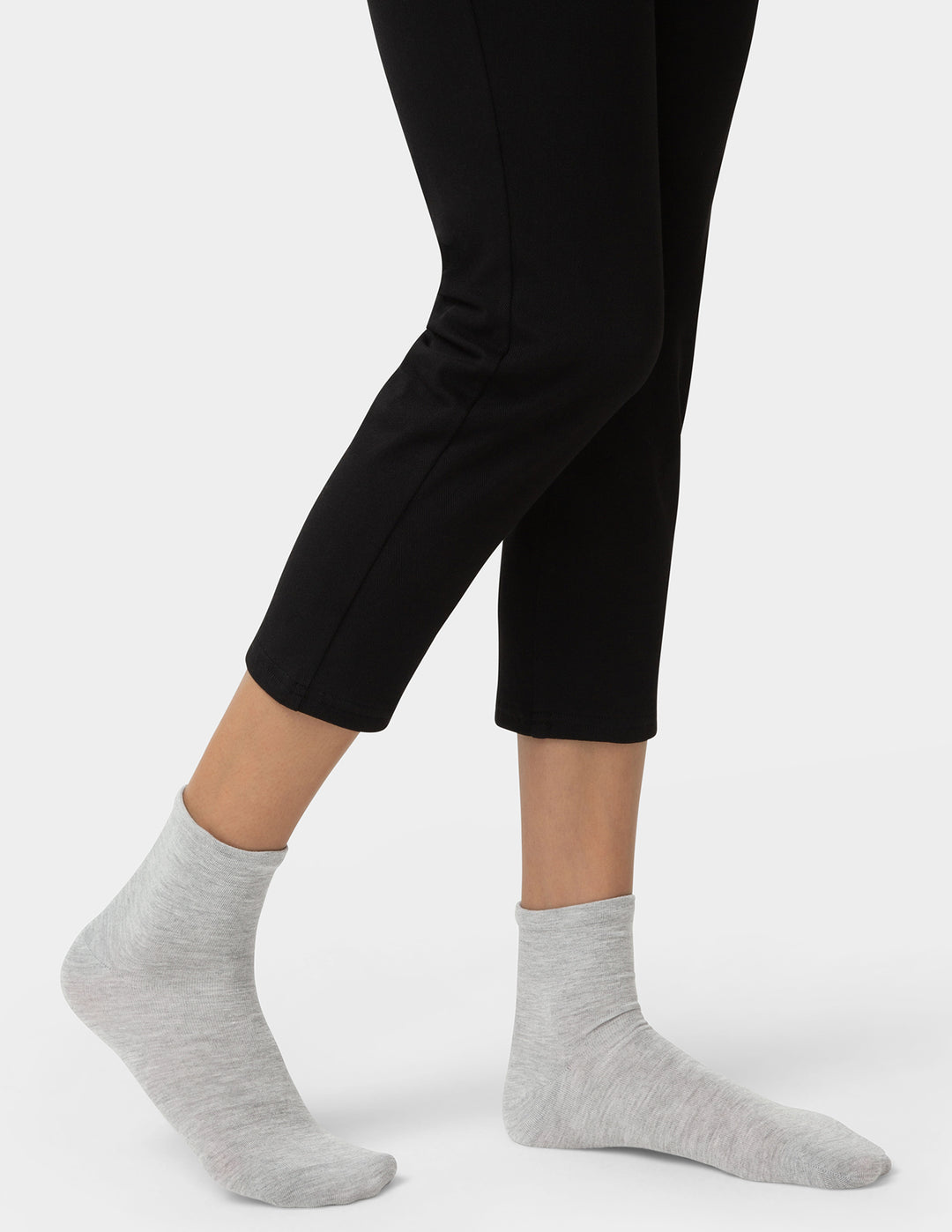 Person wearing black leggings and gray socks on a white background