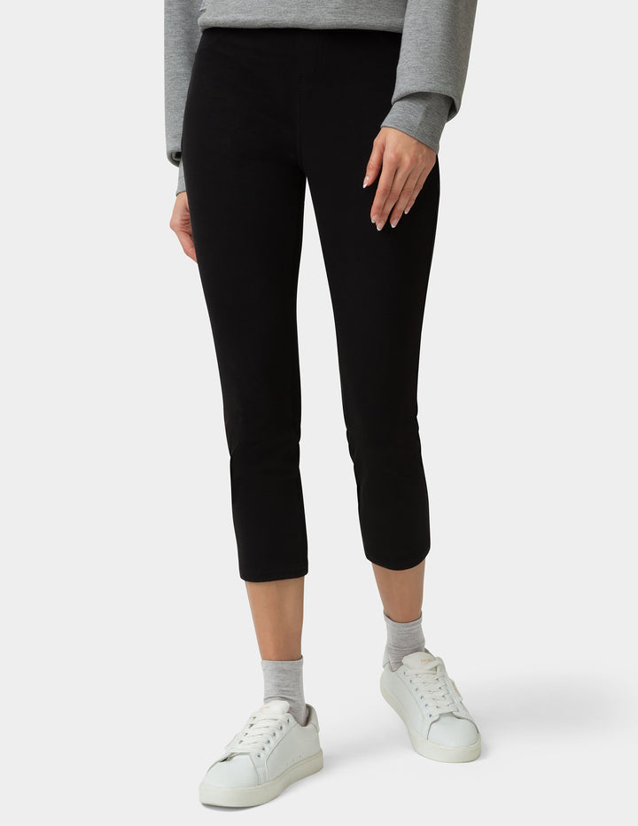 Person wearing black leggings with a gray sweater and white sneakers on a white background