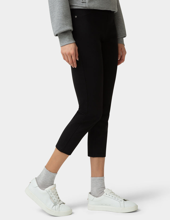 Person wearing black capri pants with a gray sweater and white sneakers on a white background