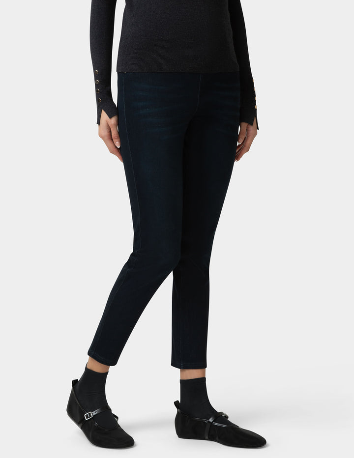 Person wearing dark blue jeans and black shoes on a white background