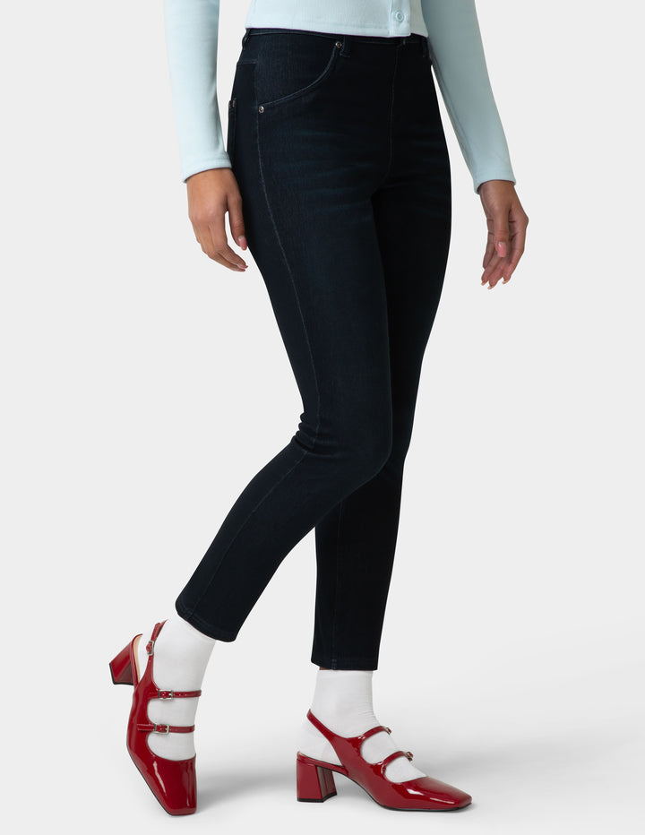 Person wearing black jeans with red shoes and white socks on a light gray background