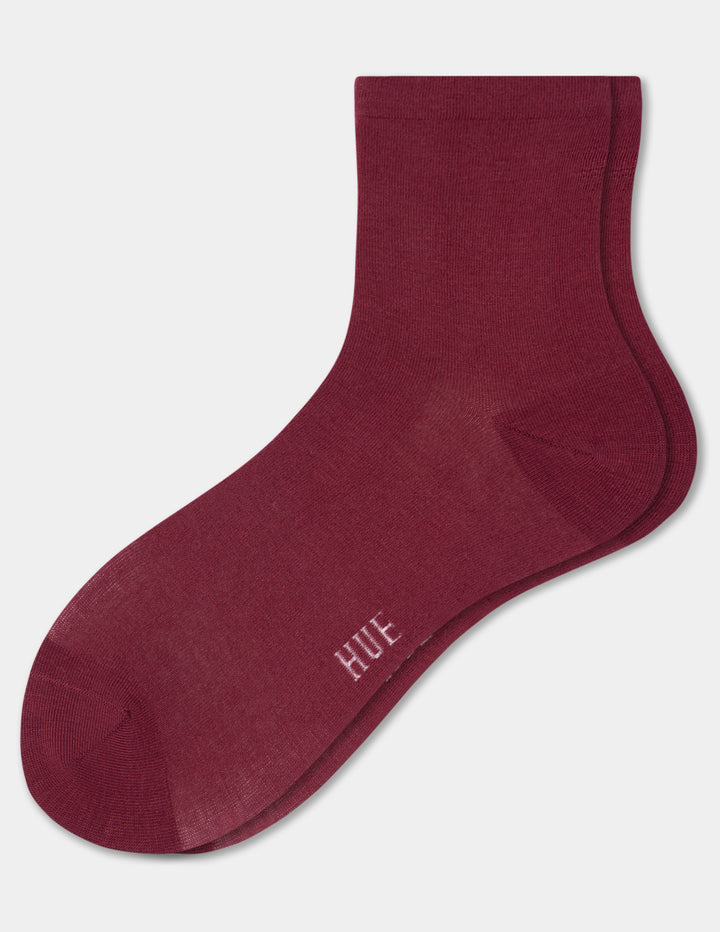 A pair of crew socks in a deep burgundy color, featuring the brand name 'HUE' printed in white near the toe, shown against a light gray background.