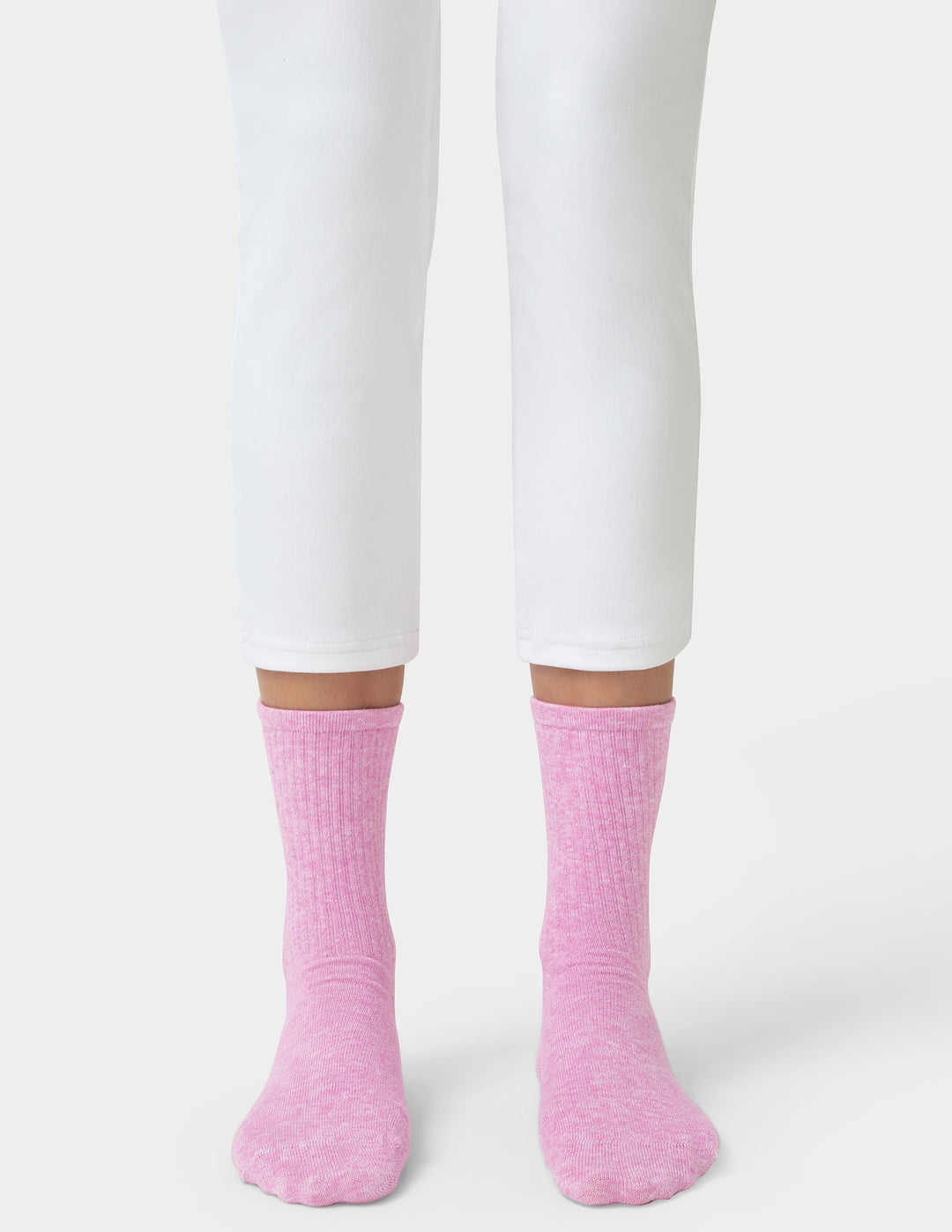Person wearing pink socks and white pants on a white background