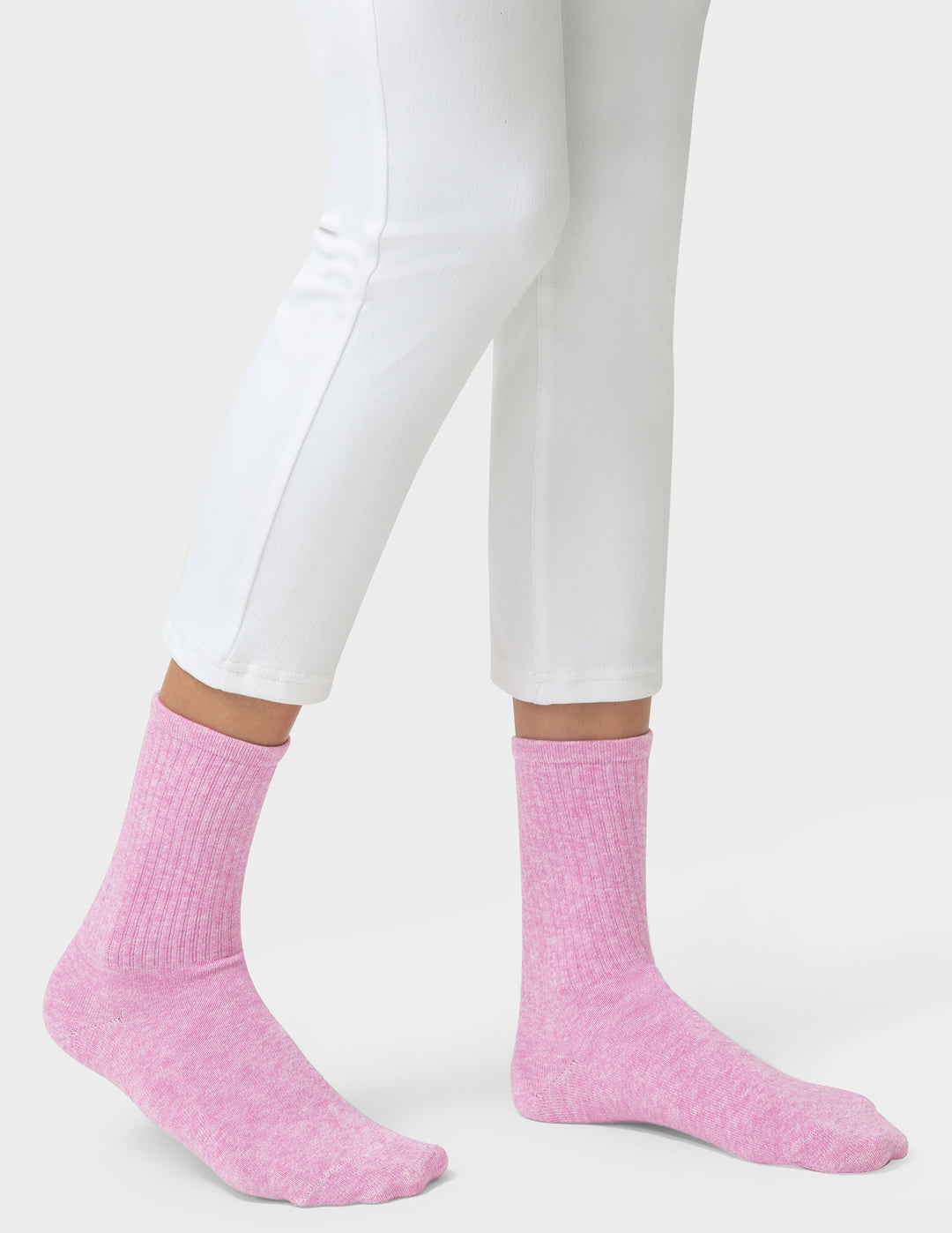 Person wearing pink socks and white pants on a light gray background