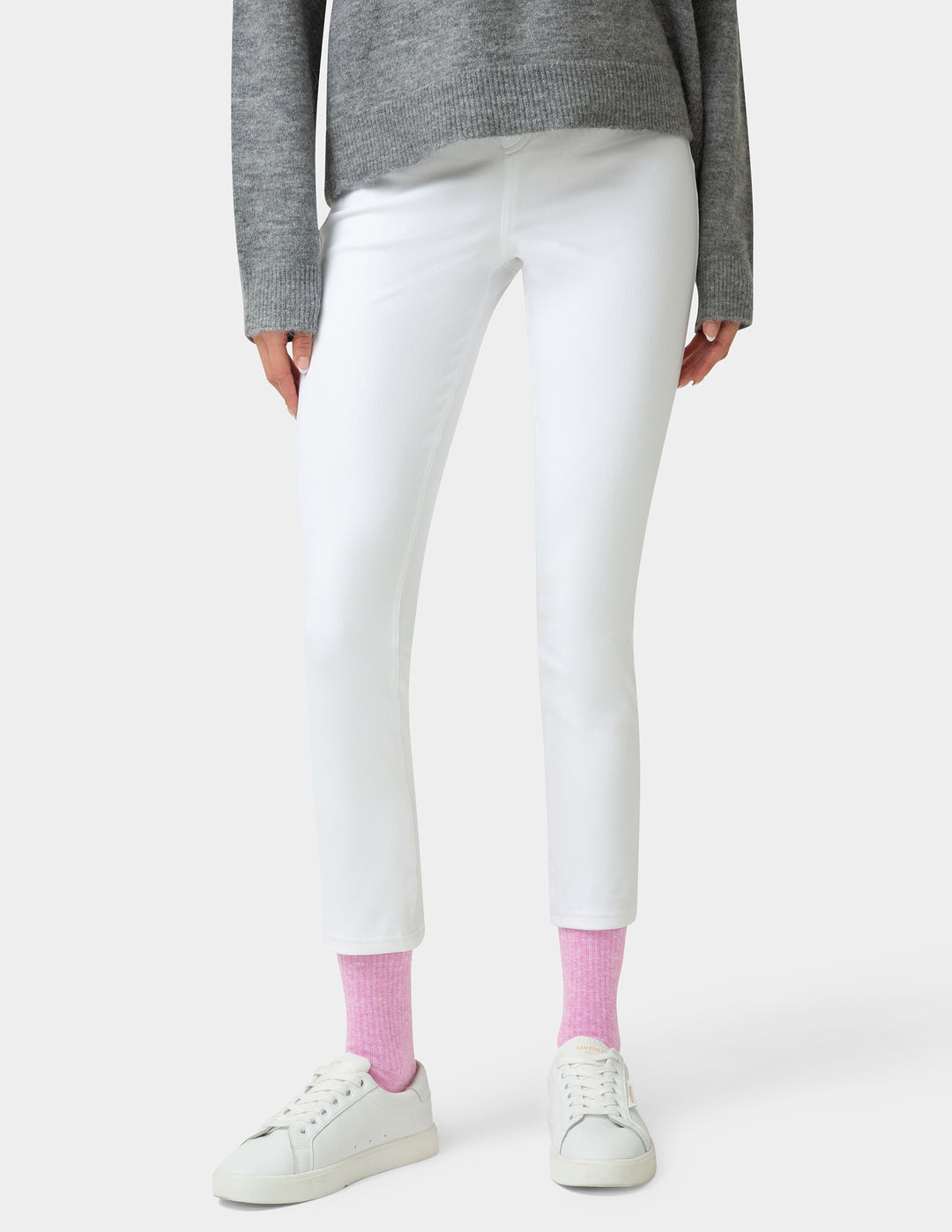Person wearing white pants, gray sweater, and pink socks on a white background