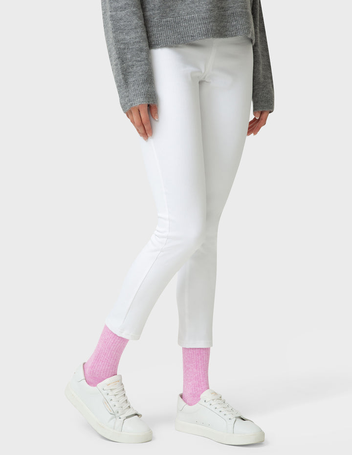Person wearing white leggings, gray sweater, and pink socks on a white background