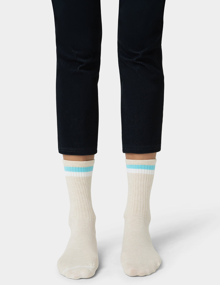 White socks with light blue stripes worn with black pants on a white background