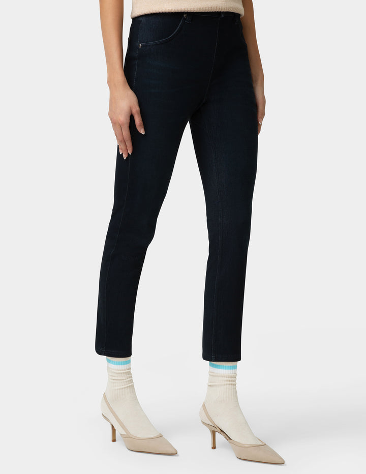 Person wearing dark jeans and beige high-heeled shoes on a white background