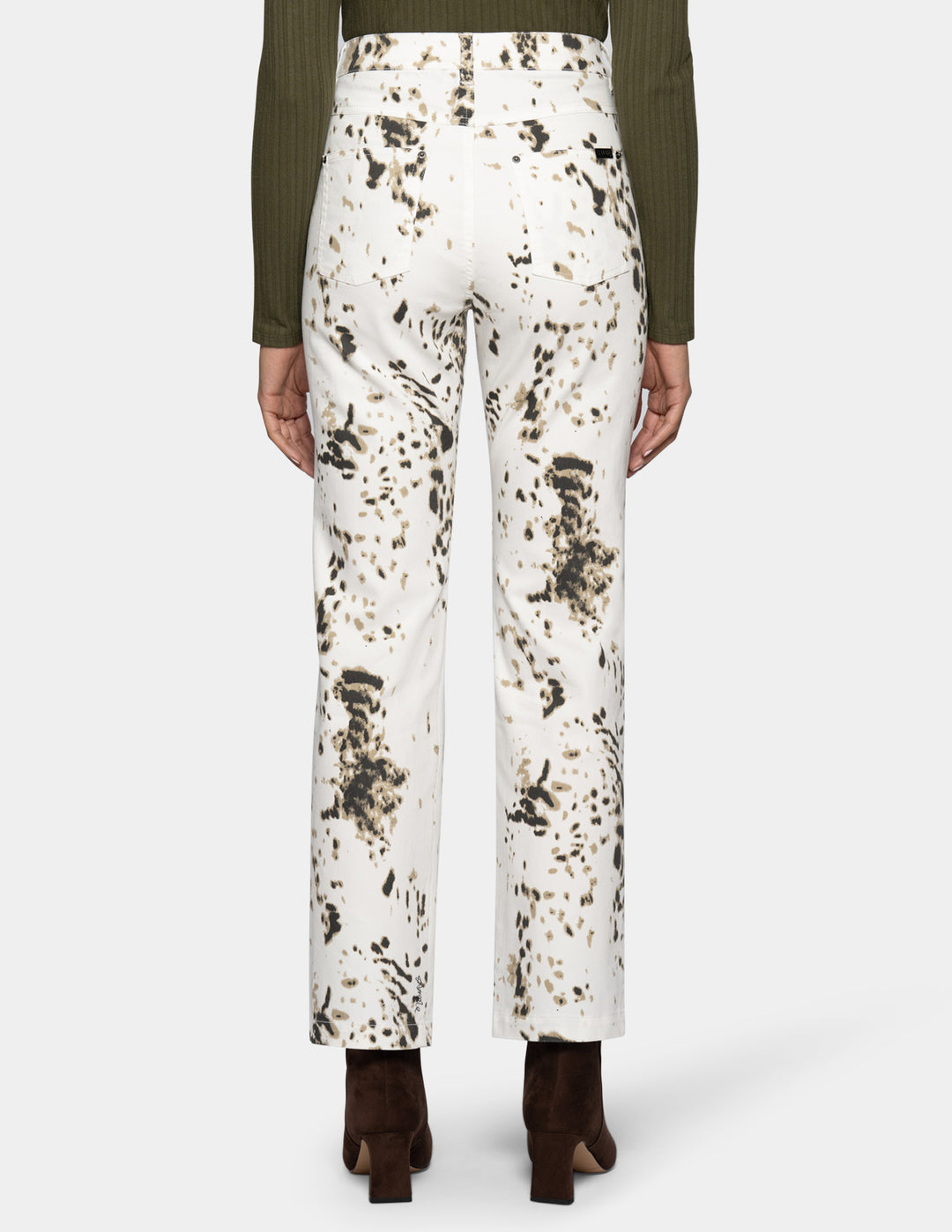 Backside view of a woman modeling white straight leg pants with a brown animal print pattern throughout.