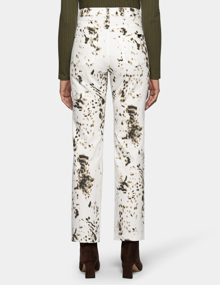 Backside view of a woman modeling white straight leg pants with a brown animal print pattern throughout.