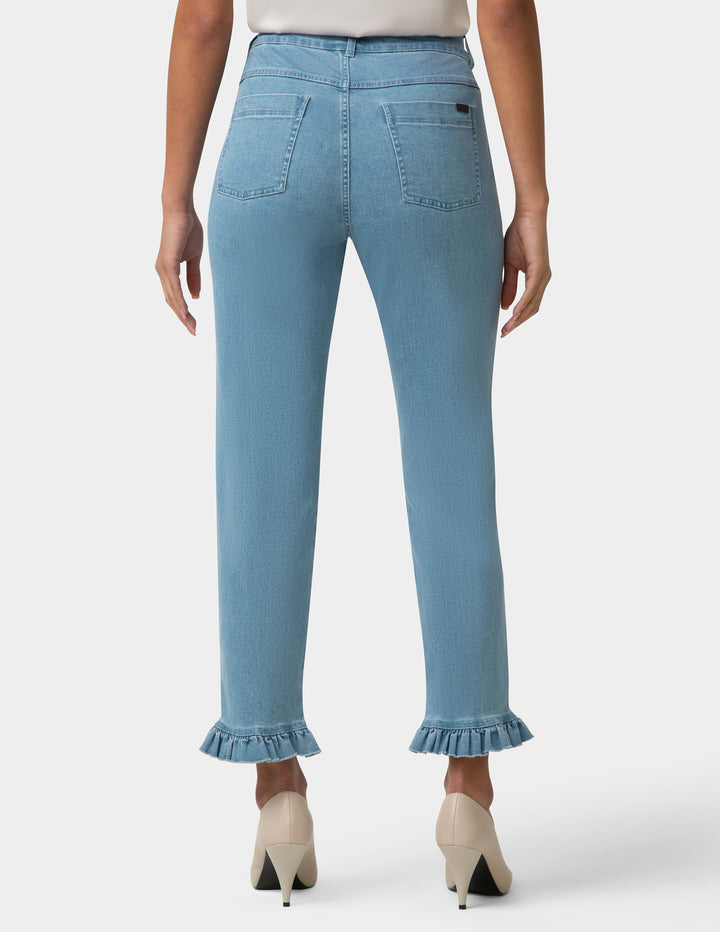 Light blue jeans with ruffled cuffs worn by a person on a white background