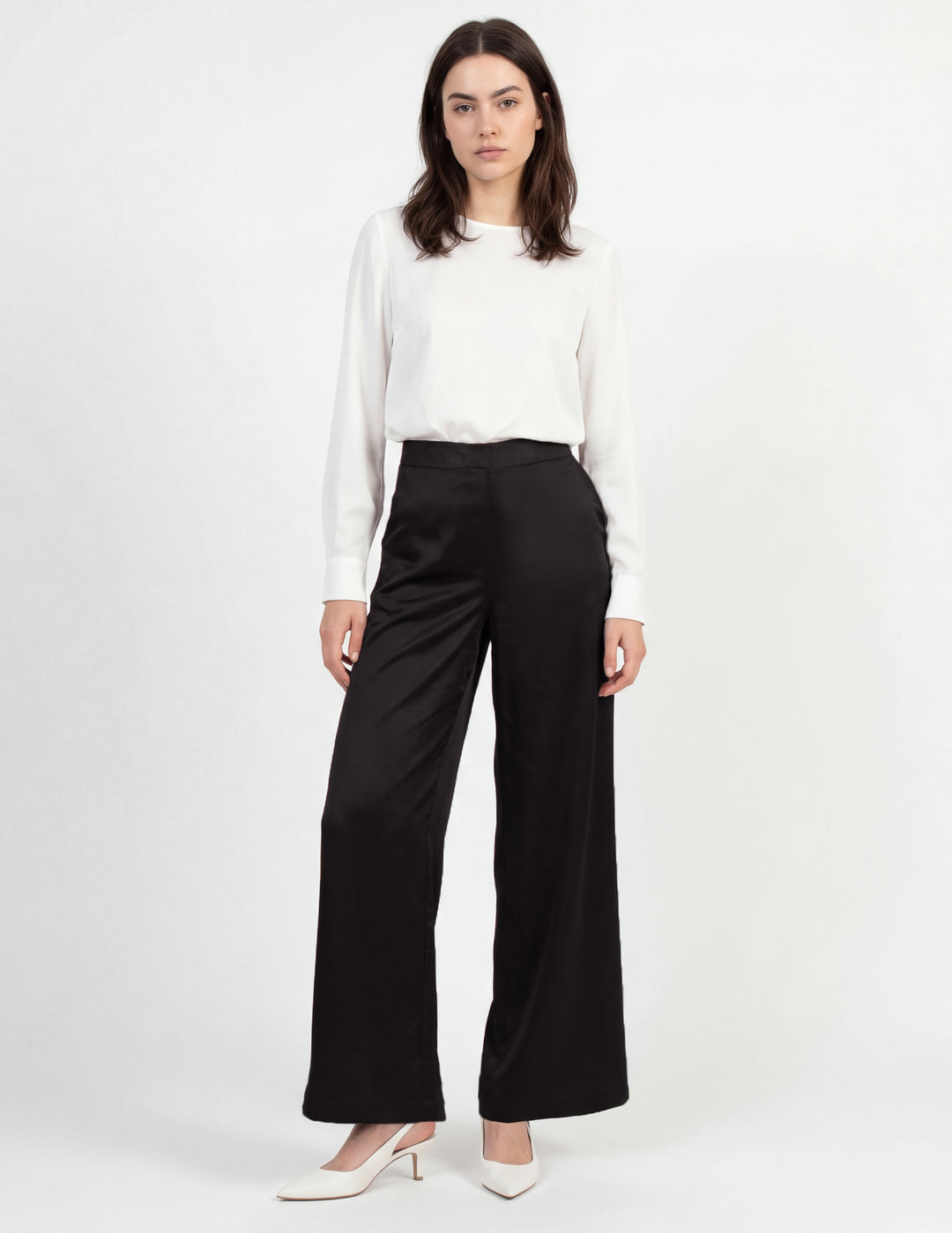 Woman wearing a white blouse and black pants on a white background