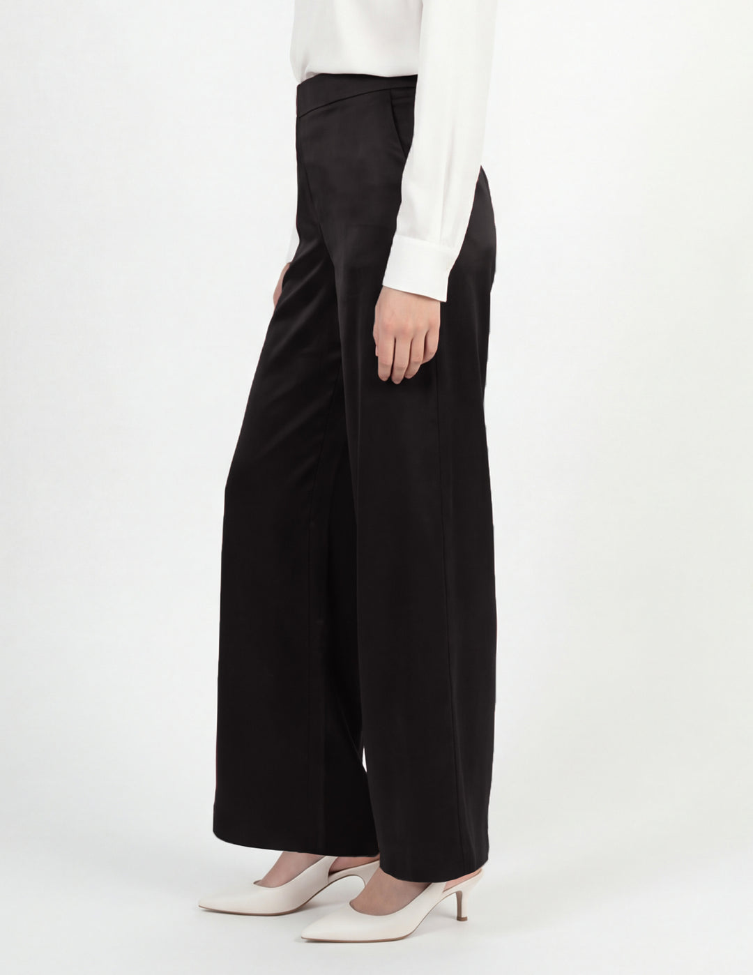 Person wearing black wide-leg pants with a white top on a white background