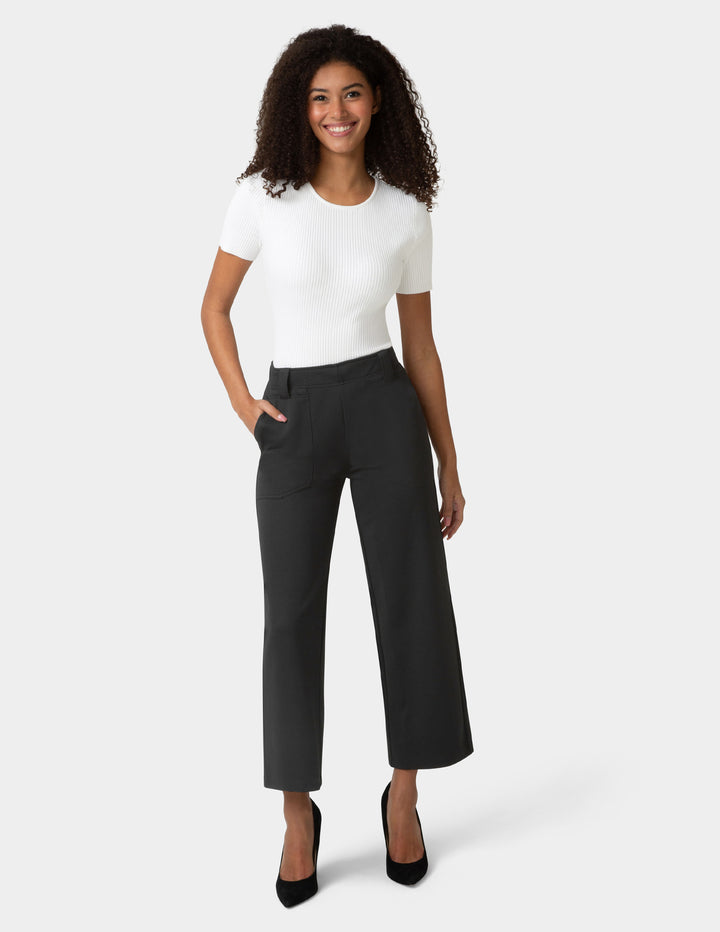 Woman wearing a white top and black pants on a white background