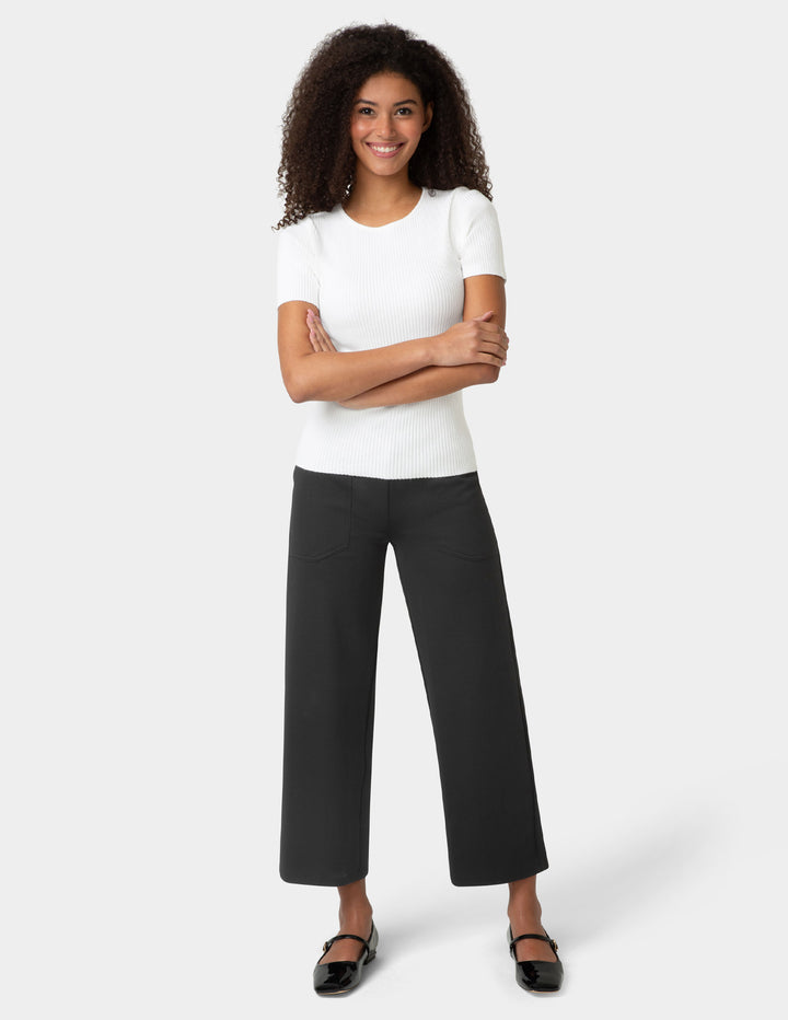 Woman wearing a white t-shirt and black pants on a white background