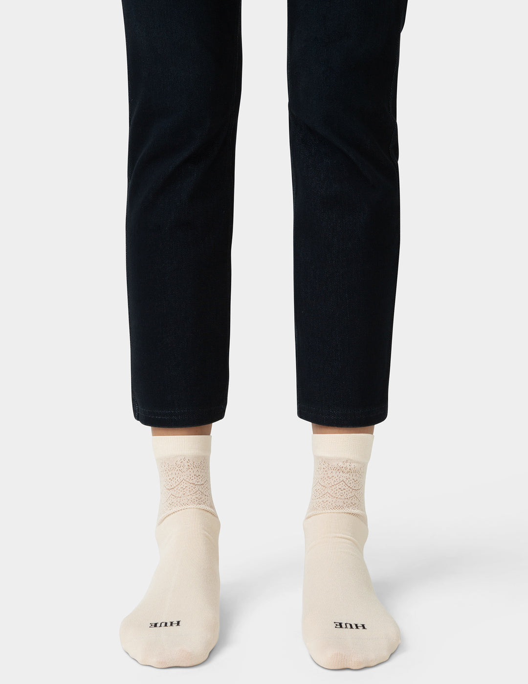 Person wearing black pants and beige socks on a white background