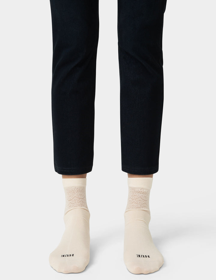 Person wearing black pants and beige socks on a white background