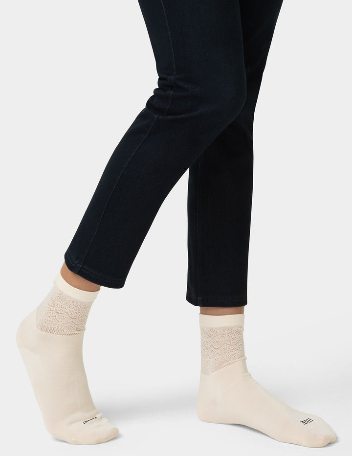 Person wearing black leggings and cream socks on a white background